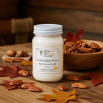 Load image into Gallery viewer, 16 oz mason Jar of Vanilla Maple Pecan hand poured candle with pecans and leaves on a wooden surface.  Southern Charm Farmhouse.

